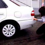 Девушка исследует автомобиль на предмет повреждений